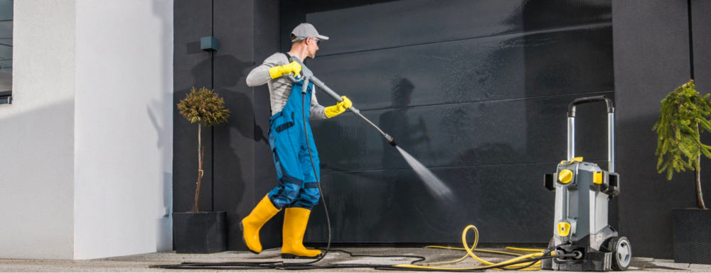 A restaurant cleaner using a high pressure washer on a wall