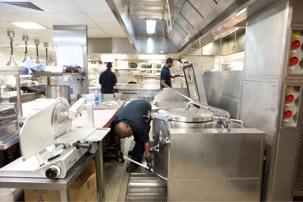A busy kitchen being cleaned by restaurant cleaners
